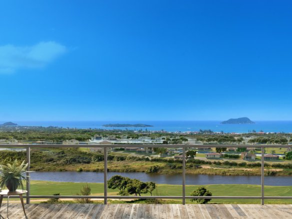 Vista da varanda para áreas verdes, lago e mar ao fundo.