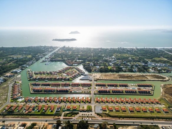 Vista aérea de casas e canais, com a faixa costeira e ilhas ao fundo.
