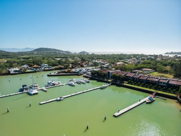 Vista aérea da marina com embarcações, píeres e casas nas margens.