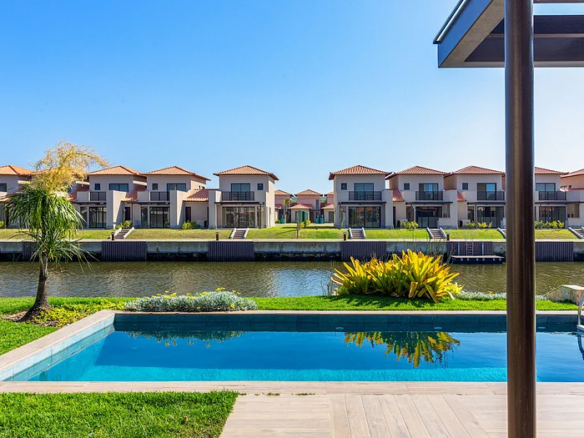 Piscina vista da varanda de uma casa, com canal e outras casas ao fundo.