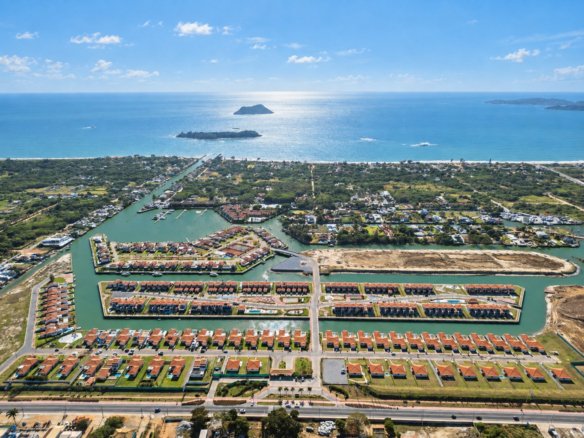Vista aérea de casas e canais, com a faixa costeira e ilhas ao fundo.