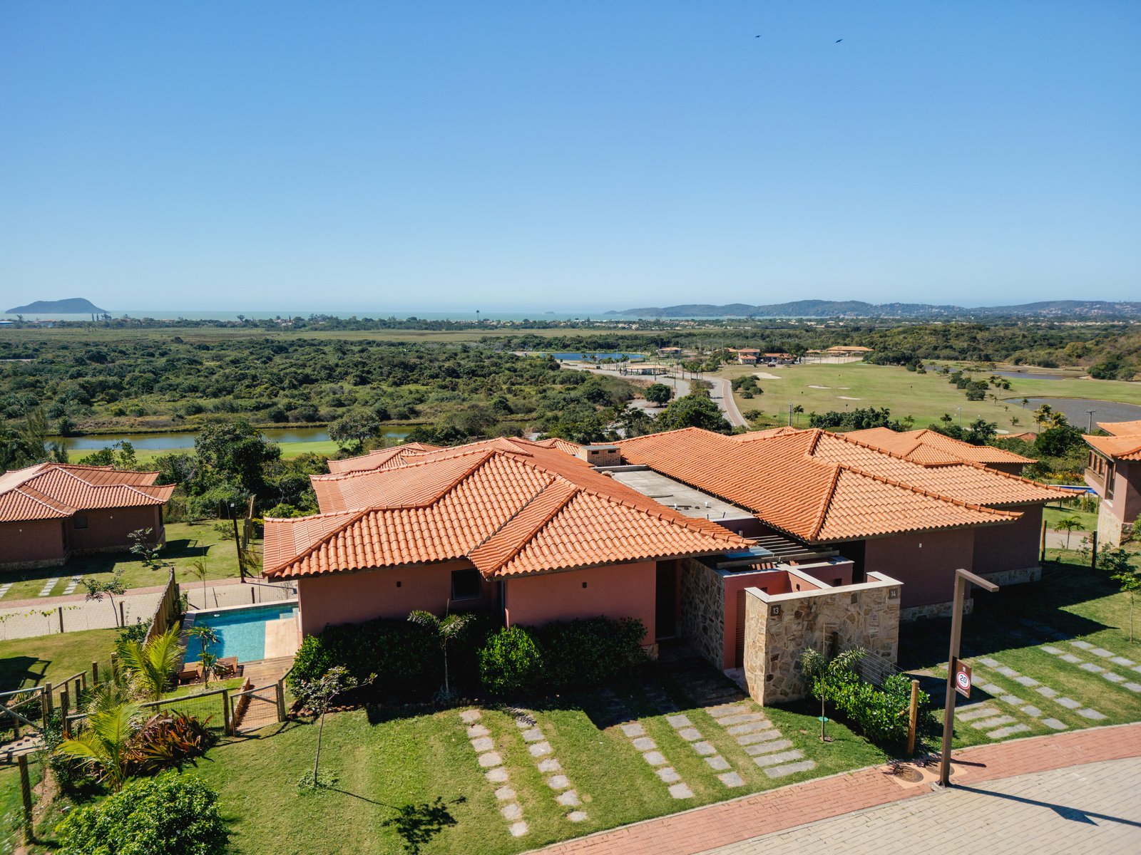 Casas de telhados cerâmicos no Ybirá, com jardins, árvores e áreas abertas ao fundo.