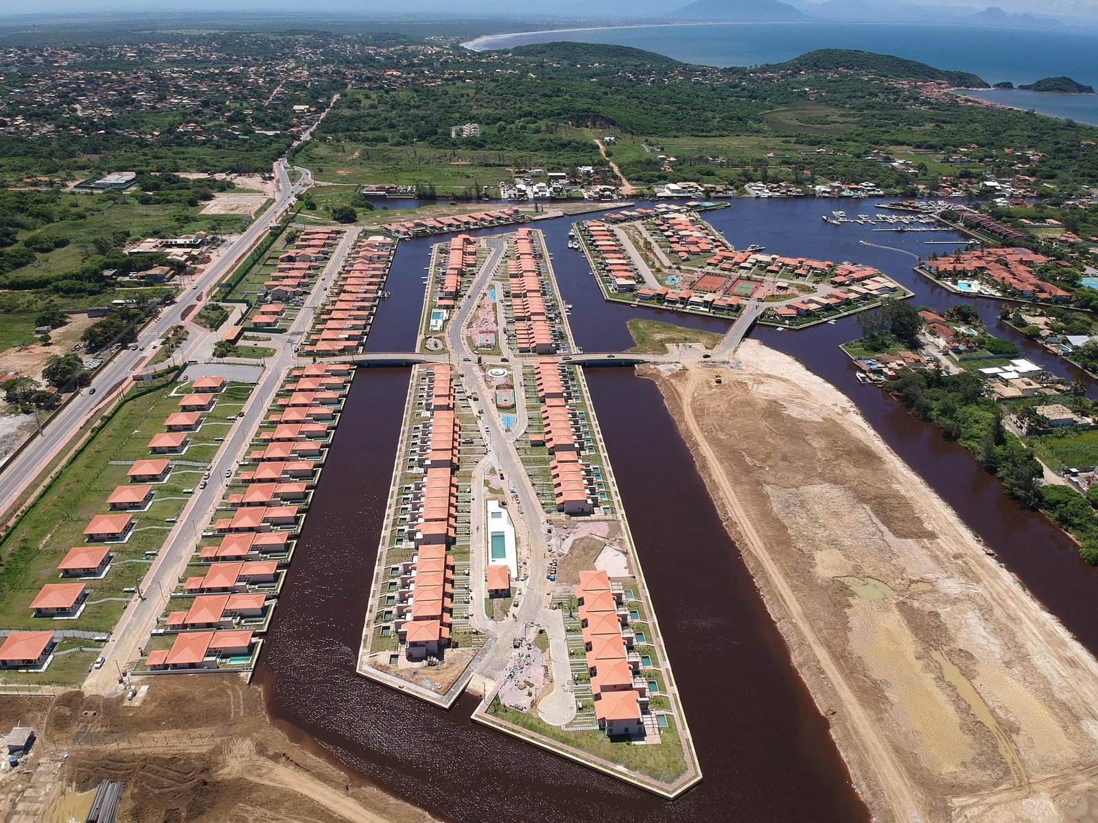 Vista aérea das ilhas de casas do Toriba entre os canais, com áreas ainda sem casas à direita (foto real)