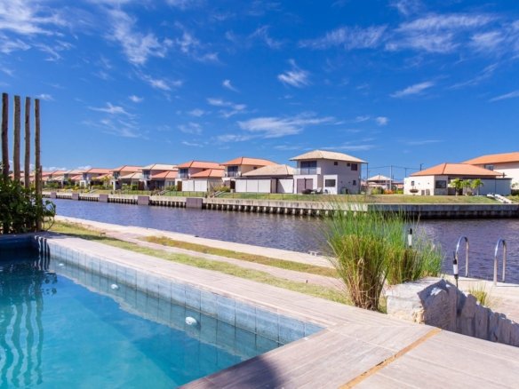 Piscina da casa 10 do Condomínio B do Toriba Norte, com o canal e as casas da outra margem ao fundo (foto real)
