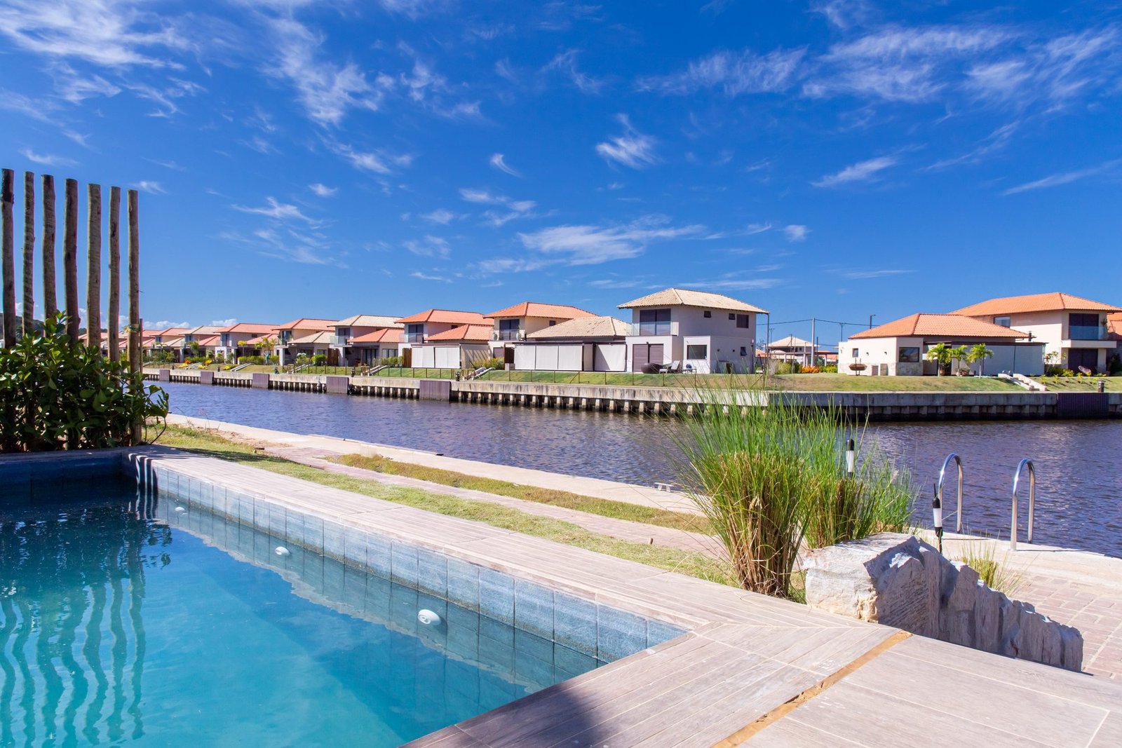 Piscina da casa 10 do Condomínio B do Toriba Norte, com o canal e as casas da outra margem ao fundo (foto real)
