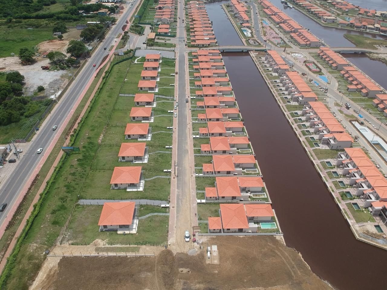 phoco-sync-4f54744fa84c4269-ff7dcfda857f Vista aérea de um canal do Toriba entre duas fileiras de casas, com a estrada à esquerda (foto real)