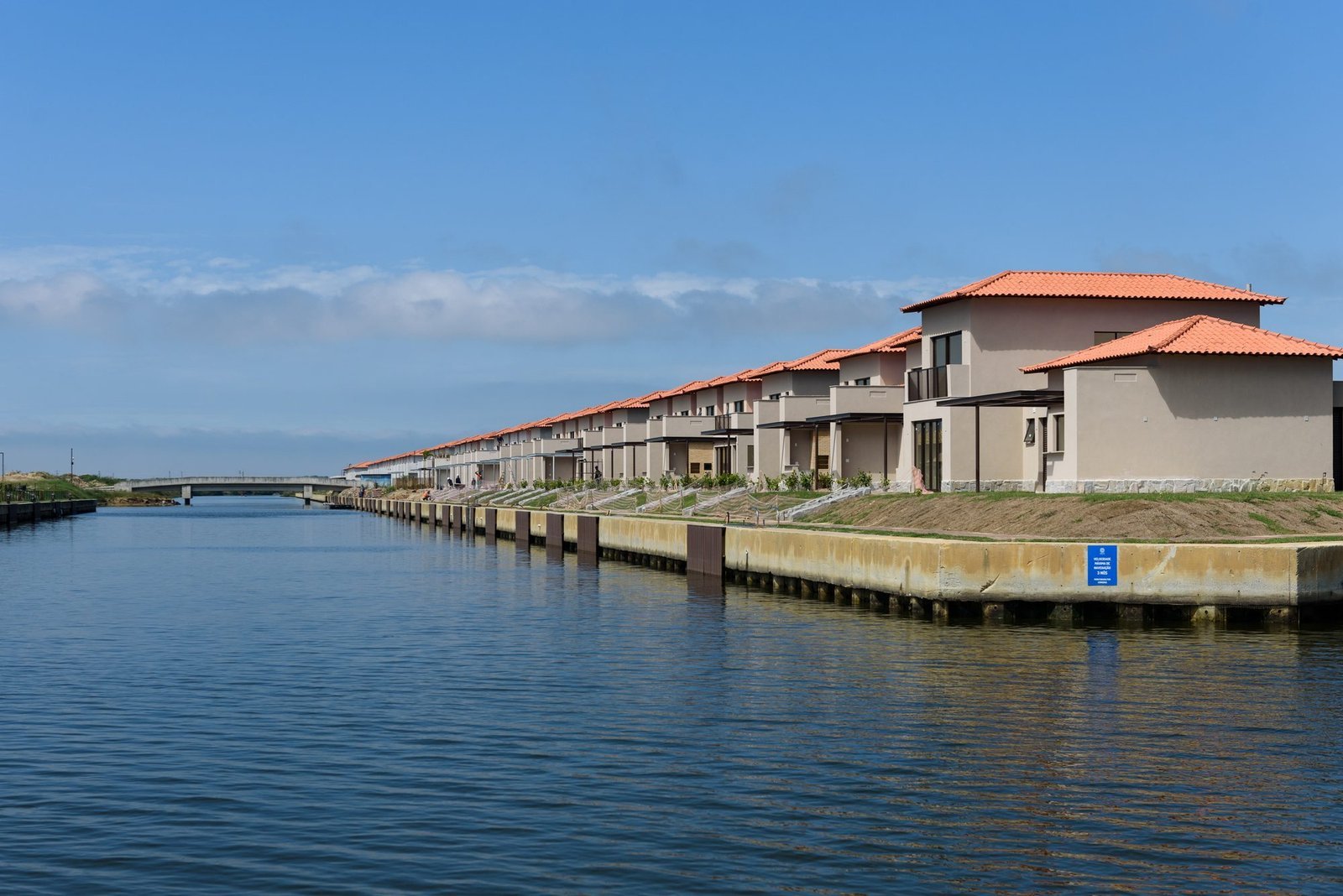 Canal do Toriba Norte, com a fileira de casas à margem e uma ponte ao fundo (foto real)