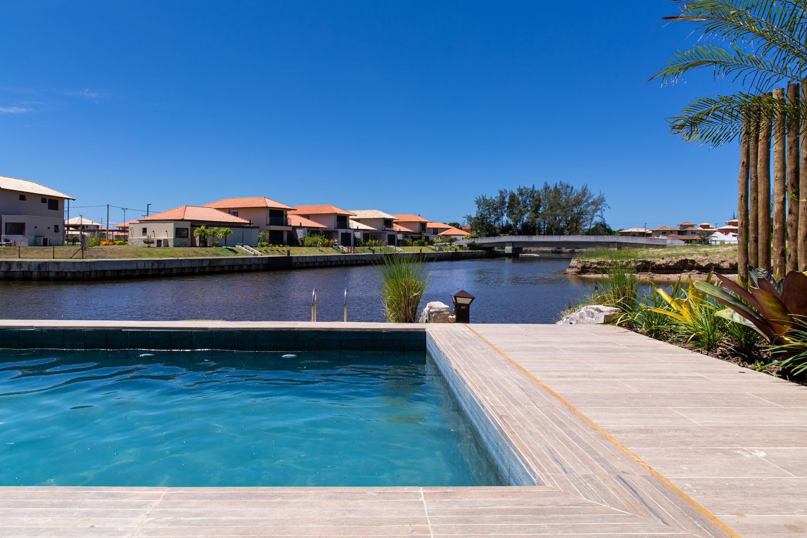 Piscina da casa 10 do Condomínio B do Toriba Norte, com deck de madeira e o canal ao lado (foto real)