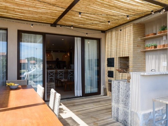 Varanda da casa 9 do Condomínio A do Toriba Norte, decorada, com mesa, churrasqueira e cobertura de bambu (foto real)