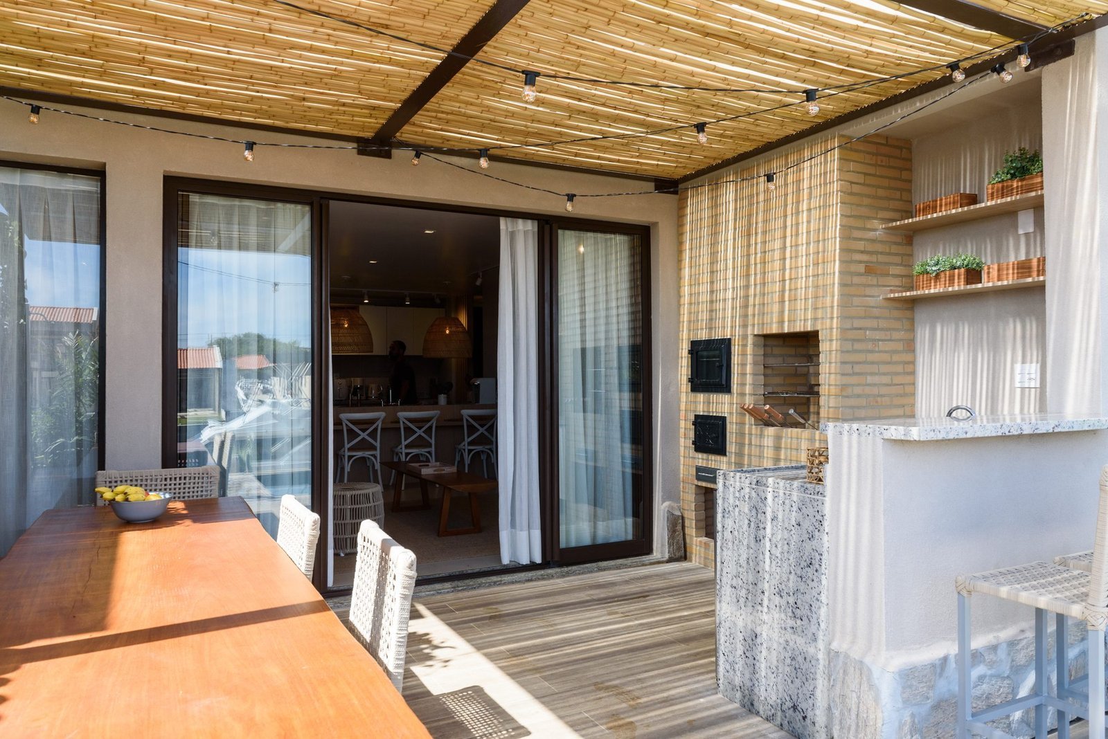 Varanda da casa 9 do Condomínio A do Toriba Norte, decorada, com mesa, churrasqueira e cobertura de bambu (foto real)