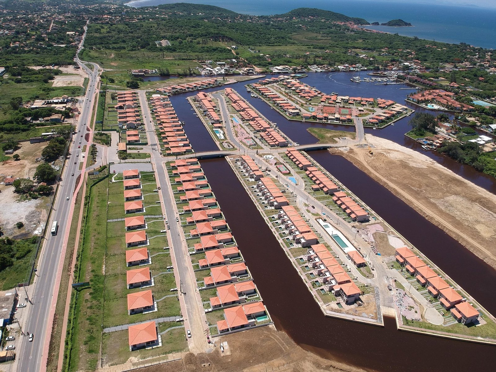 Vista aérea dos canais do Toriba, com as casas nas ilhas, a estrada à esquerda e o mar ao fundo (foto real)