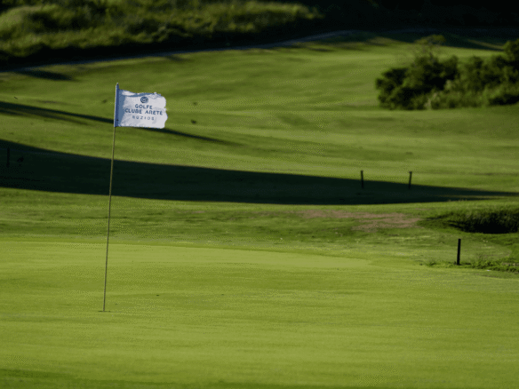 Green do campo de golfe com a bandeira branca do Golfe Clube Aretê Búzios (foto real)
