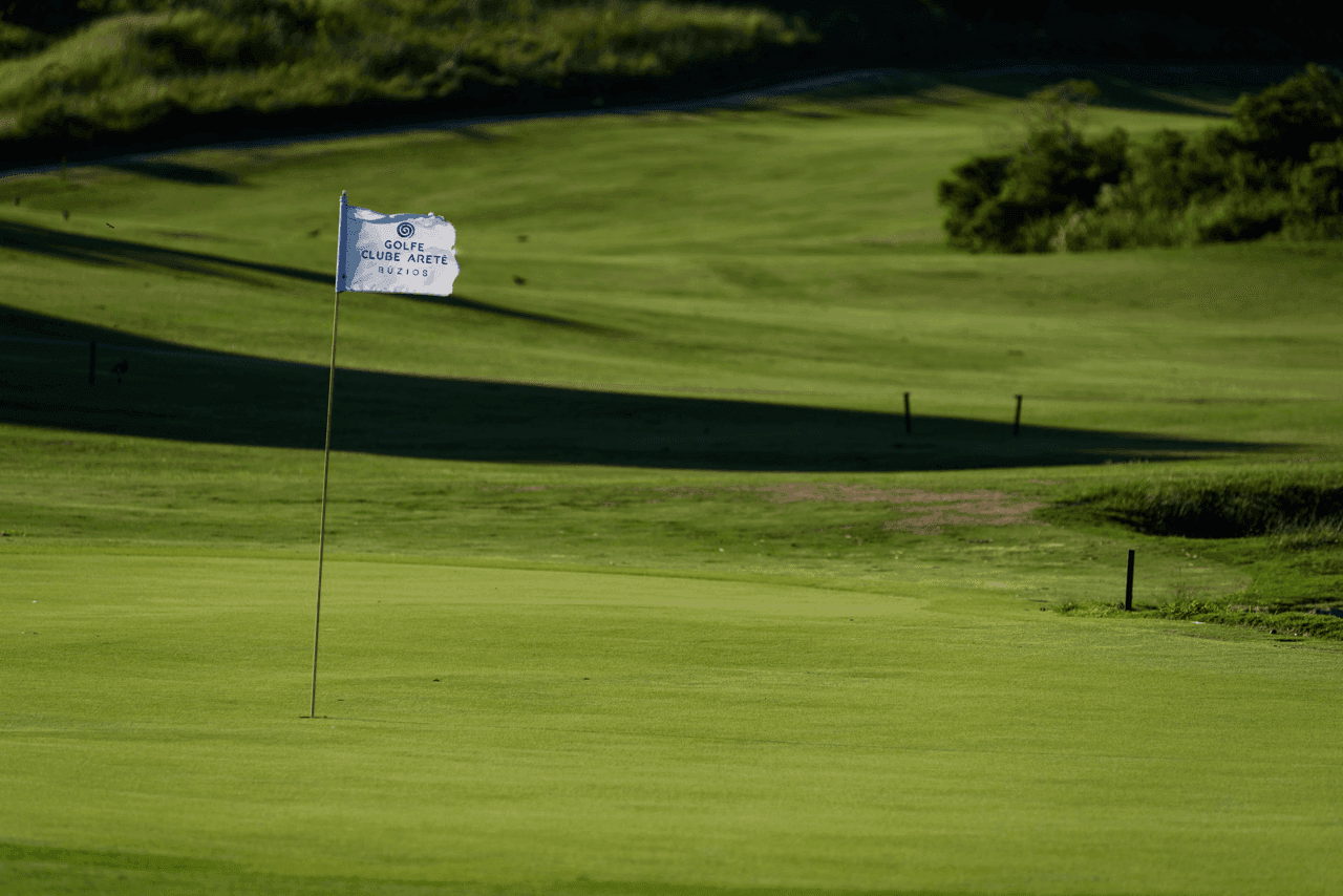 Green do campo de golfe com a bandeira branca do Golfe Clube Aretê Búzios (foto real)