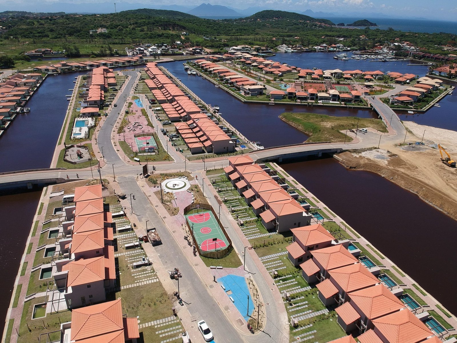phoco-6304 Vista aérea de uma área de lazer do Toriba, com quadra e piscina, entre casas e canais (foto real)