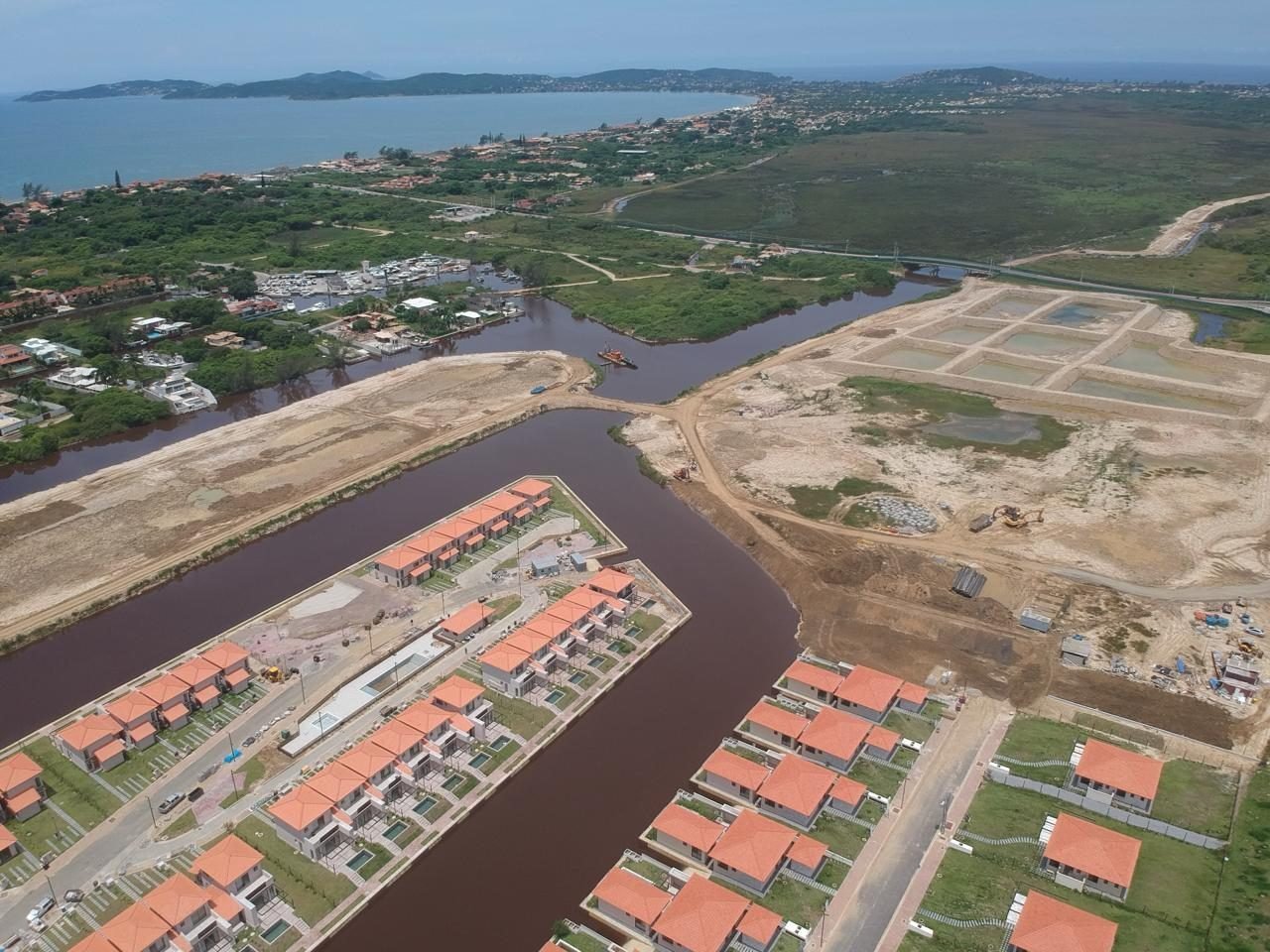 phoco-6307 Vista aérea de um canal do Toriba, com casas à margem, áreas ainda sem casas e o mar ao fundo (foto real)